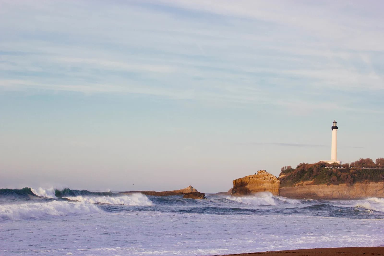 The Phare de Biarritz on a cliff above heavy Atlantic surf.