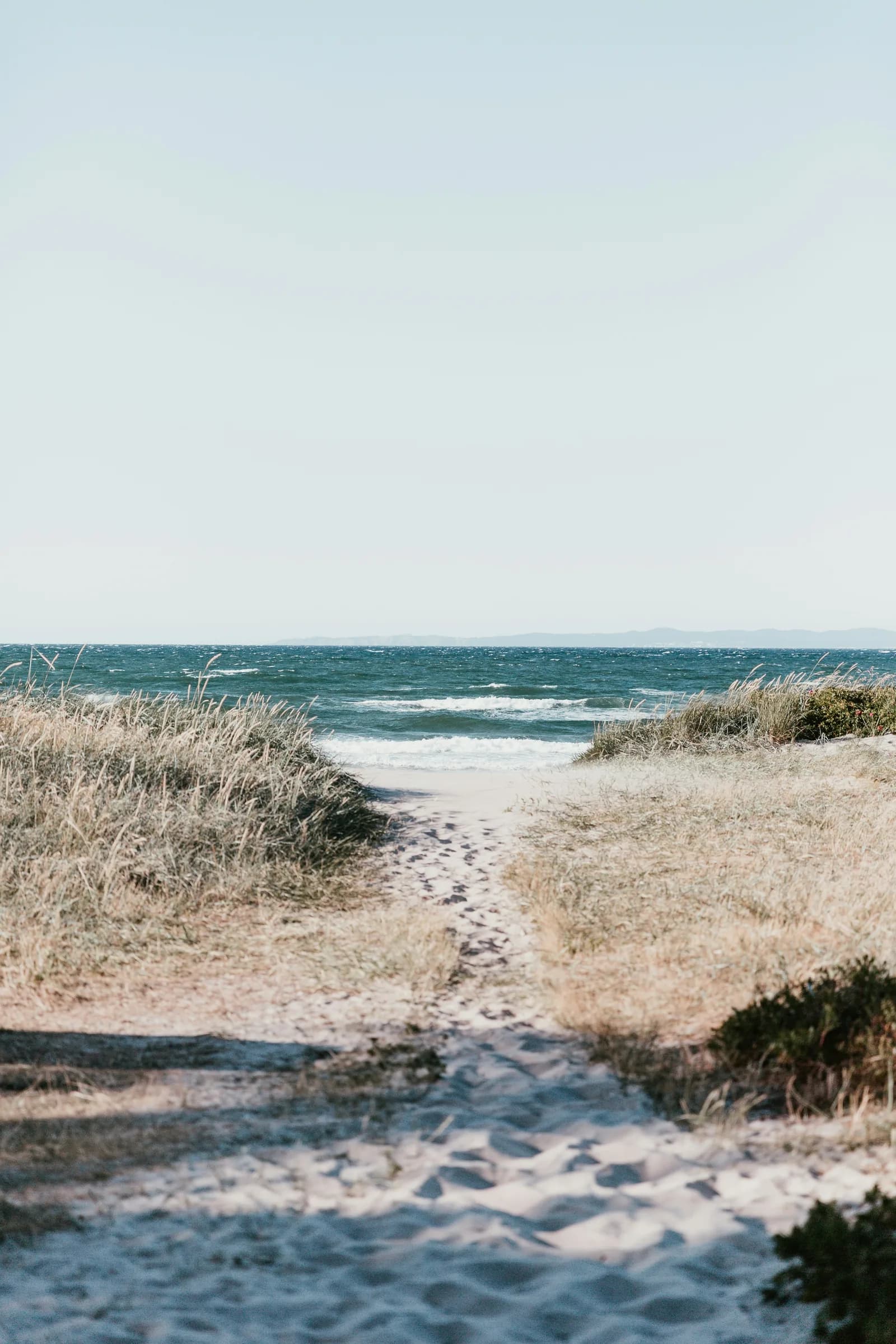 Sandy footpath through dune grass to bright Baltic sea