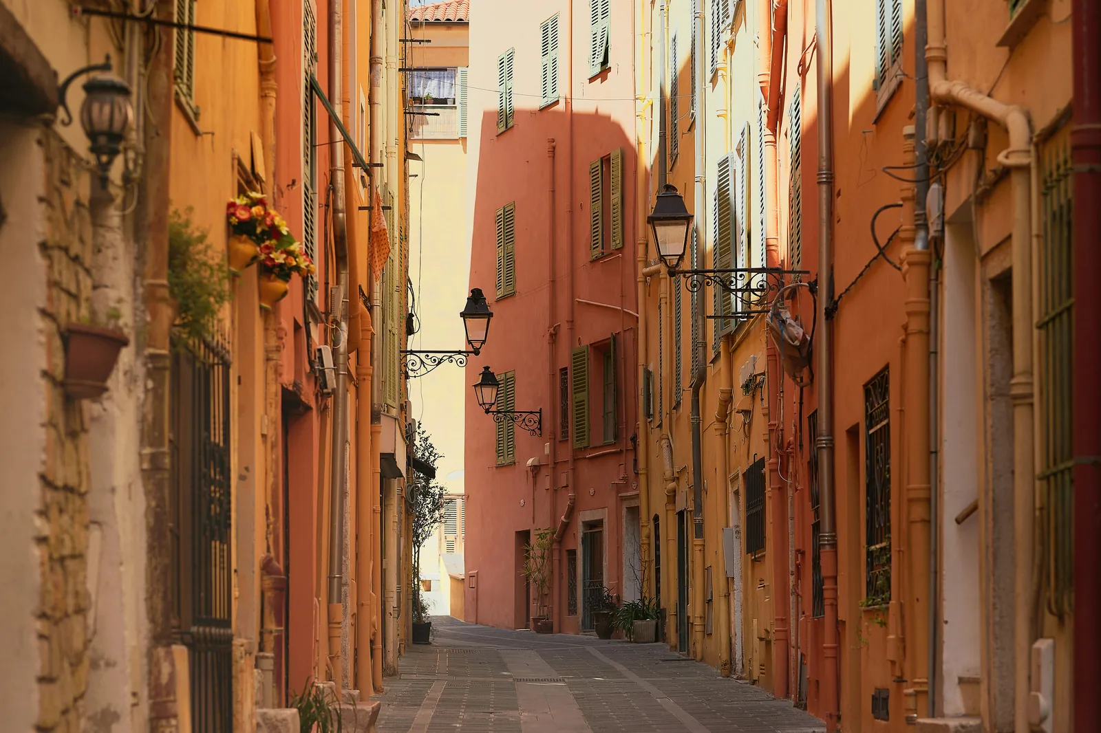 Narrow lane between coral and yellow Riviera houses with shuttered windows